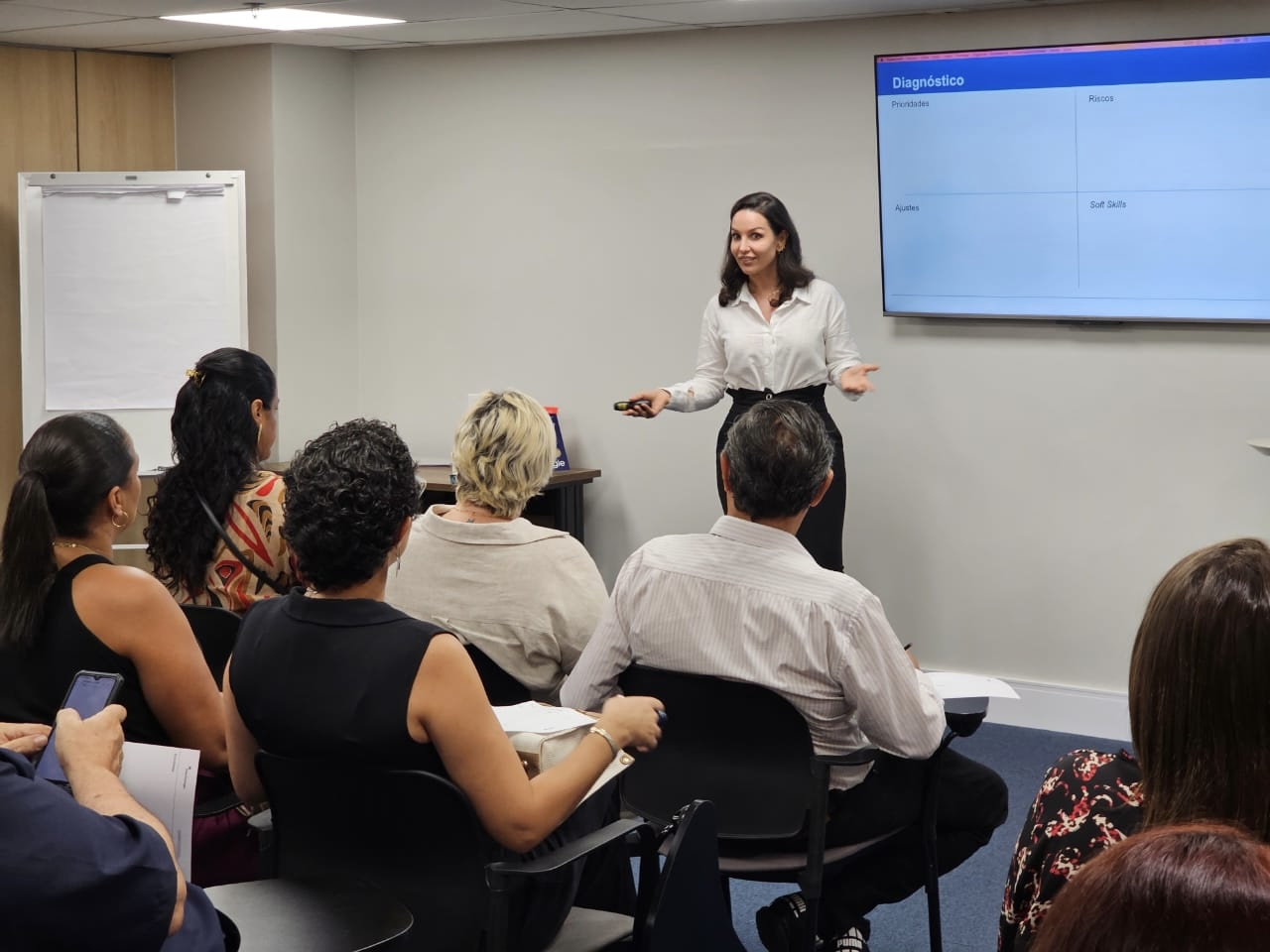Hag Schultz conduzindo uma apresentação para um público em ambiente corporativo.